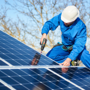 Electrician mounting solar panel on roof of modern house